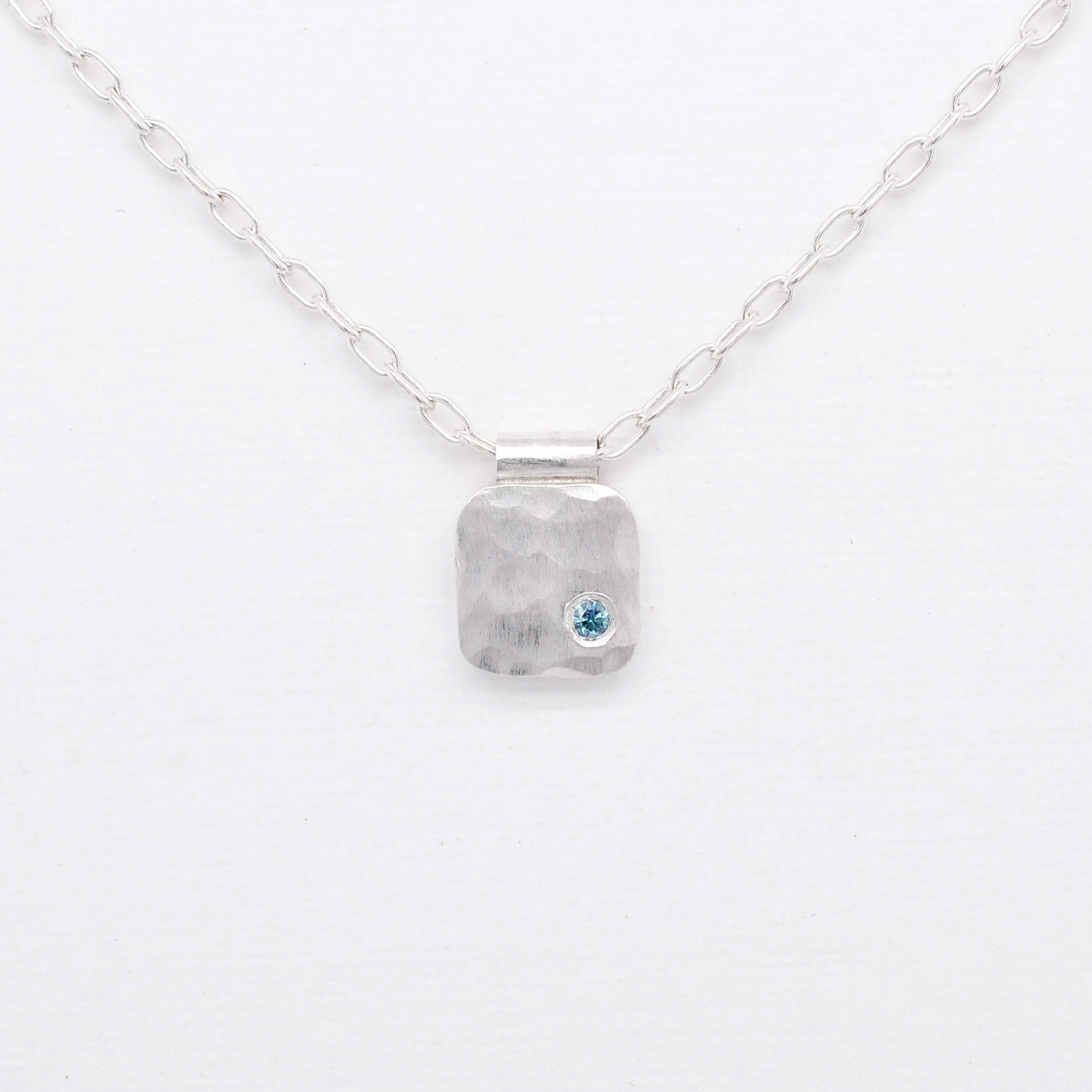 Hammered silver cell pendant with teal blue diamond. Handmade by EC Design Jewelry in Minneapolis, MN.